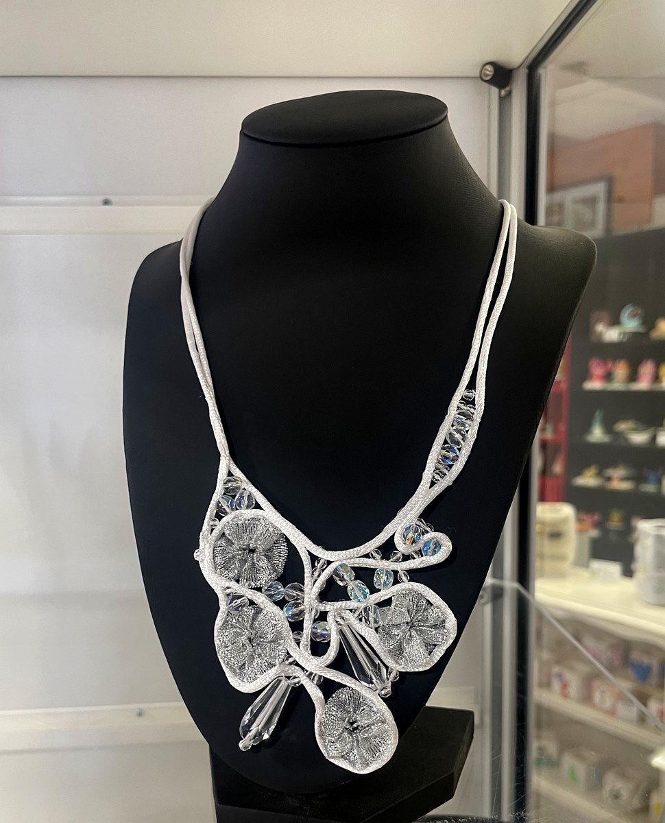 Collier plastron fait main : fleurs tissées au fil métallique argenté, gouttes de verre taillé à facettes en pendants, montées sur un cordon blanc tressé.